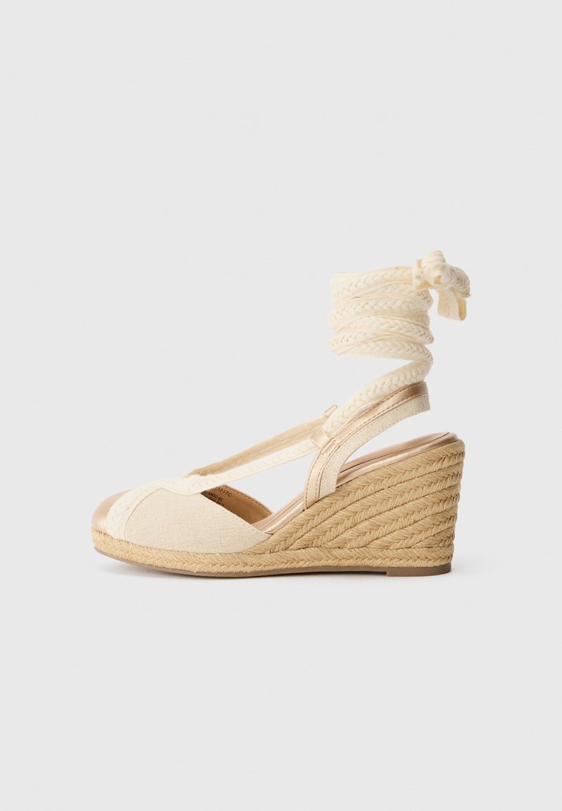 Sandale compensée beige avec talon en jute tressé et lien à nouer autour de la cheville, bout ouvert et dessus en tissu.