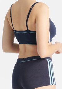 Marinblå sport-bh med justerbara strappar, ljusblå detaljer och en figursydd design, tillsammans med matchande marinblå shorts med blå sträck.