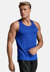 Blaues Sportoberteil mit rundem Ausschnitt, aus strukturiertem Stoff. Hat ein figurbetontes Design und das Markenlogo auf der Brust.