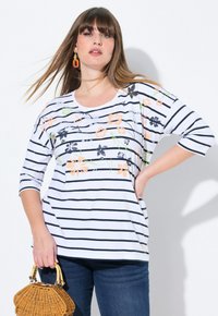 Gestreiftes Hemd in Weiß und Marineblau mit floraler Stickerei in Orange, Grün und Schwarz. Verfügt über einen runden Halsausschnitt und Dreiviertelärmel.