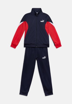 Granatowy dres Puma z czerwono-białymi blokami kolorów na rękawach, kurtką na zamek i dopasowanymi spodniami z logo Puma na piersi i nogawce.