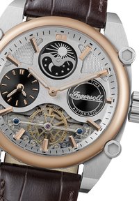 Automatisch horloge met een zilver en roségouden roestvrijstalen kast, brown leren band, ingewikkelde tandwieldetails en meerdere wijzerplaatkenmerken.