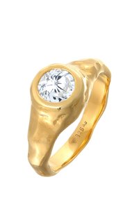 Guldfarvet ring med en fremtrædende, rund, klar ædelsten indsat i et struktureret bånd med organiske, flydende former. Markeret med "925Ag."