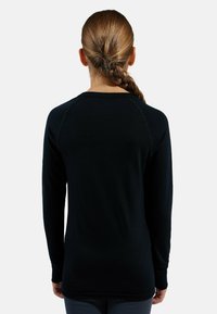 Long-sleeve black shirt with a round neckline and raglan sleeves. Smooth texture with stitching accents along the seams.