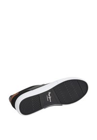 Svart joggesko med hvit gummisåle, som har et teksturert bunnlag, brunt skinn-aksent og merke på siden og innleggssålen.