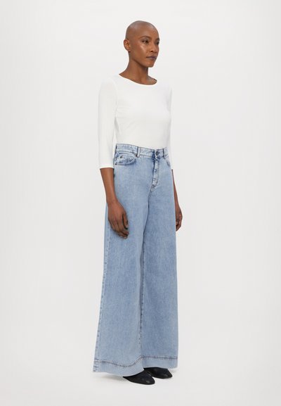 Light blue wide-leg denim jeans with a high waist, five pockets, and a raw hem, paired with a fitted white long-sleeve top.