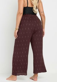 Pantalones de pierna ancha burdeos con un acabado texturizado, que presentan un sutil patrón plateado y una cinturilla elástica. Acentos decorativos en dorado.
