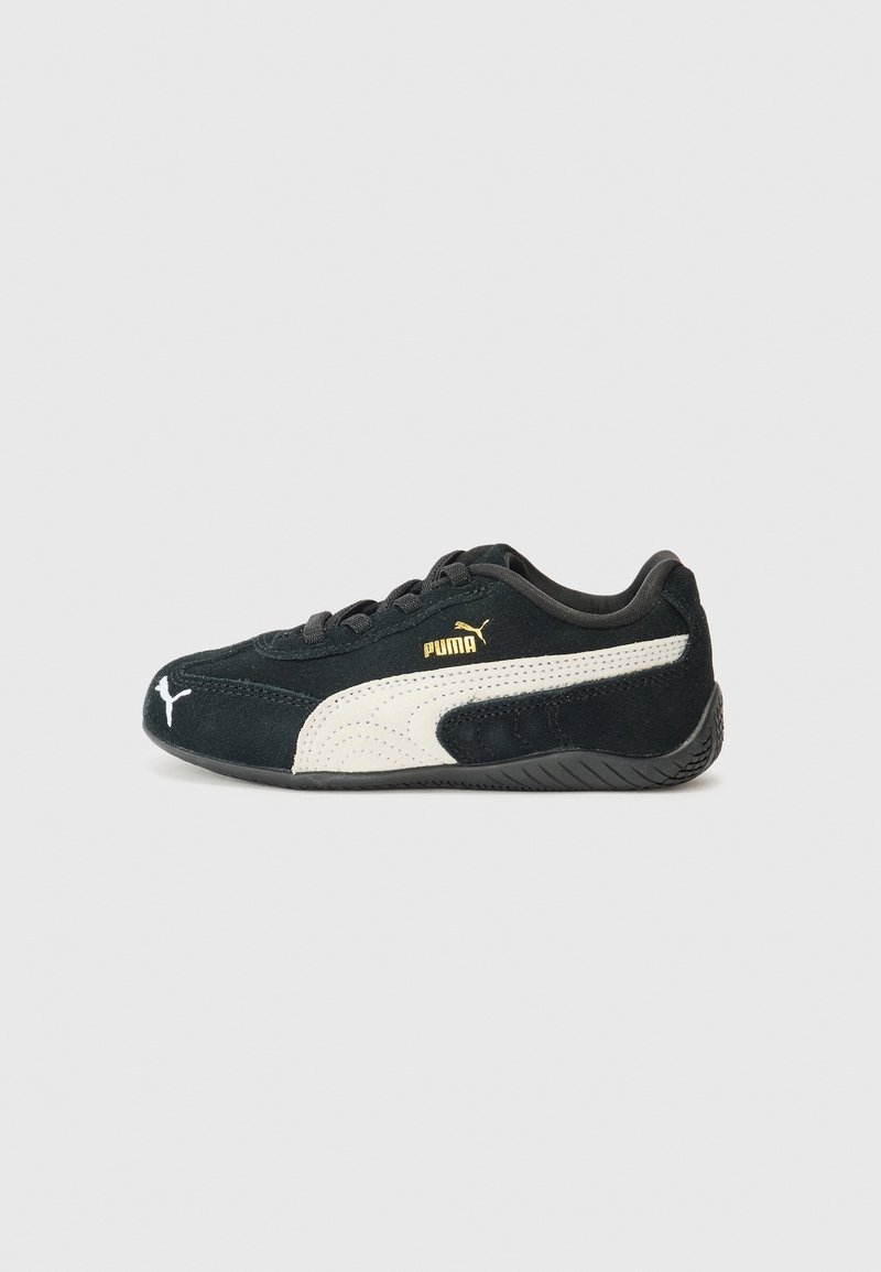 Baskets Puma noires avec bande blanche et logo, semelle basse profil et lacets, vues de profil gauche sur fond clair.