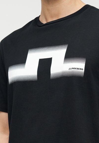 Μαύρο βαμβακερό t-shirt με έντονο λευκό γεωμετρικό λογότυπο με διαβαθμισμένες κουκκίδες και μια μικρή ετικέτα της μάρκας τοποθετημένη στο σχέδιο.