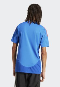 T-shirt de sport bleu à manches courtes, col rond et détails en mesh. Présente des accents rouges sur les épaules et un ourlet arrondi à l'arrière.