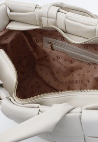 Borsa a tracolla in pelle bianca con design intrecciato, interno con rivestimento in tessuto rosa e testo beige con marchio. Dotata di una tasca con zip.