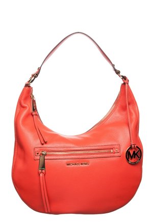 Sac à main Michael Kors en cuir rouge avec une forme arrondie, une poche frontale zippée, des accessoires dorés et un pendentif rond avec le logo MK suspendu à la bandoulière.
