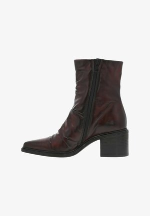 Bottine en cuir marron avec un nez pointu, fermeture zippée et un talon bloc empilé. Présente une texture froncée sur le dessus.