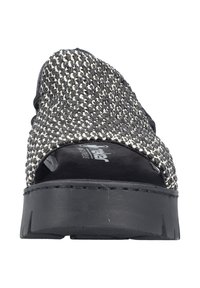 Sandale tressée noir et blanc avec une épaisse semelle noire et un bout ouvert. La tige présente un tissu texturé et des accents noirs unis.