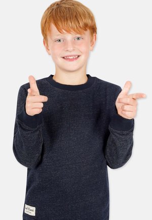 Dunkelblaue Sweatshirt aus strukturiertem Stoff, mit gerippten Bündchen und Ausschnitt. Kind posiert mit nach oben zeigenden Fingern, lächelt vor einem hellen Hintergrund.