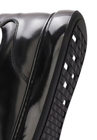 Black glossy leather boot with a rounded toe, featuring a textured rubber sole and stitched detailing along the side and upper.