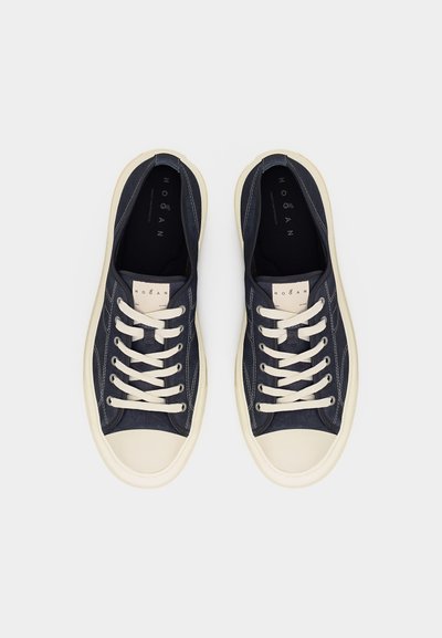 Pereche de adidași negri și albi cu talpă joasă, cu șireturi albe, capace din cauciuc pe vârfuri și etichetă cu logo pe limbă, văzuți de sus.