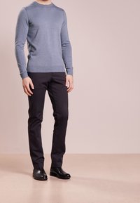 Pull bleu clair à manches longues associé à un pantalon noir droit et des bottes en cuir noires. Design simple avec poignets et ourlet côtelés.