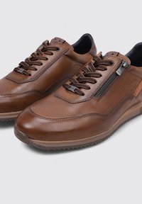 Zapatillas de cuero marrón con un acabado suave, que presentan un diseño de cordones, cremallera lateral y suela de goma con un patrón de textura.