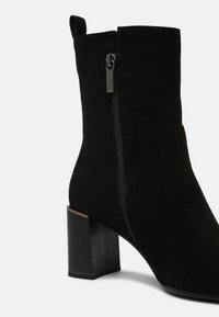 Czarne zamszowe botki za kostkę z bocznym zamkiem, kwadratowym obcasem i zaokrąglonym noskiem. Charakteryzują się gładką fakturą i minimalistycznym wzornictwem.