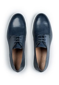 Scarpe in pelle blu scuro con una finitura liscia, suole bianche, design con lacci e una fodera interna marrone. Stile minimalista con linee pulite.