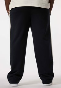 Marineblauwe joggingsbroek met crèmekleurige zijkanten, gemaakt van zachte katoenmix stof. Voorzien van een elastische tailleband en manchetten voor optimaal comfort.