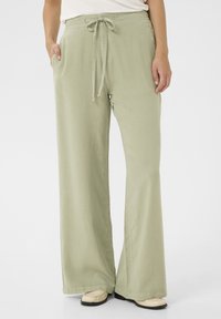 Svetlozelené široké nohavice vyrobené z mäkkej, textúrovanej tkaniny. Majú elastický pás so sťahovacou šnúrkou a bočné vrecká.