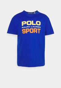 Blå kortärmad T-shirt med texten "POLO Ralph Lauren SPORT" i gult, vitt och orange centrerad på framsidan.