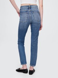 Jeans de ganga azul de cintura alta com um corte justo, apresentando dois bolsos traseiros, uma bainha limpa e um detalhe de borda crua no tornozelo.