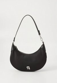 Musta olkalaukku sirpaleisella muotoilulla, valmistettu sileästä keinotekoisesta materiaalista. Siinä on hopeanvärinen vetoketju ja tunnistettava pieni logo.