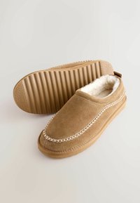 Kollaste nubuknahast susside sisemus on kunstkarvast, kaunistatud õmblustega ning neil on kummist ribikonts. Omab kandmise mugavuse tagamiseks kandmisel tõmbeauk.