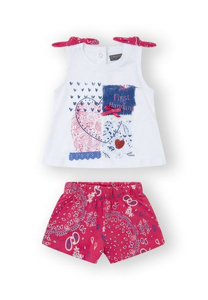 Top sin mangas blanco con tirantes de lazo, presenta patrones mixtos en azul y rojo. Pantalones cortos rosas con estampado paisley y cintura elástica.