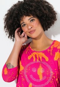 Rosa und orange Batik-Oberteil mit rundem Ausschnitt, drei Viertel langen Ärmeln und einem mit Strass besetzten Smiley-Gesicht auf der Vorderseite. Weicher Stoff.