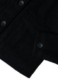 Giacca in lana nera con texture, sezione che mostra due tasche a patta con bottone e tre bottini neri con marchio "CECIL".