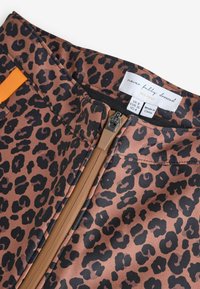 Spodnie w cętki lamparta w brązowym kolorze z czarnymi plamami, wykonane z gładkiej tkaniny, zapinane na suwak, z pomarańczowym akcentem materiału na pasie.