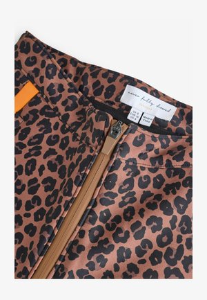 Leoparda raksta brūnas bikses ar melniem plankumiem, izgatavotas no gludas auduma, ar rāvējslēdzēja aizdari un oranžu auduma akcentu jostasvietā.