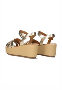 Gouden metallic wedge sandalen met een dikke beige platform, voorzien van kruisbanden en een gesp. Soepele textuur met decoratieve accenten.