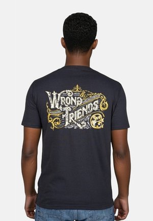 Zwarte katoenen t-shirt met een decoratieve "WRONG FRIENDS" graphic in het wit en goud, met sierlijke krullen en zwirls op de achterkant.