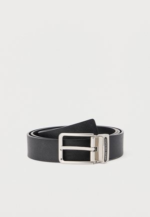 Zwarte leren riem met textuur, voorzien van een zilverkleurige rechthoekige gesp en het Armani Exchange-logo op de sluiting, opgerold op een witte achtergrond.
