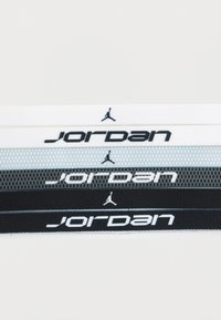 Τέσσερα κορδόνια σε λευκό, γκρι, μαύρο και μαύρο δίχτυ, με το λογότυπο «Jordan» σε αντίθετο λευκό χρώμα σε κάθε κορδόνι.
