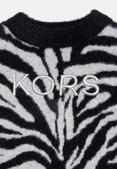 Tissu duveteux à motifs zèbre noir et blanc avec le mot "KORS" brodé en fil blanc près du haut au centre.