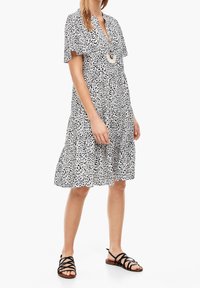 Svart och vit leopardmönstrad klänning med korta ärmar, knäppning fram och flätad fåll. Matchad med svarta sandaler med remmar.