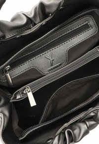 Interno della borsa a tracolla in pelle nera con più scomparti, incluso un taschino con zip. Presenta una consistenza morbida e un design arricciato nella parte superiore.