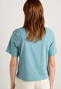 Light blue short-sleeved shirt with a relaxed fit, made of soft fabric. Hem is slightly curved, showing a minimalistic design with no patterns.