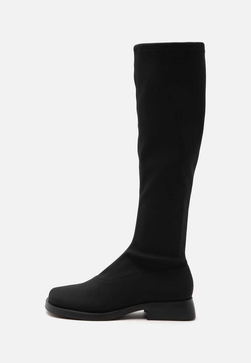Botte noire montant au genou avec talon bas et bout arrondi, tige en tissu lisse, montrée du côté gauche sur fond blanc.