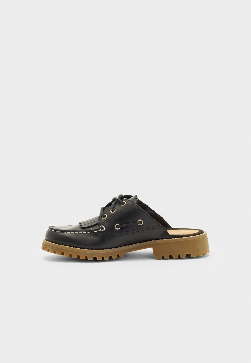 Juodas odinis šlepetės stiliaus batai su apvaliu pirštu, raištelių priekine dalimi ir storu guminiu padu. Yra metaliniai akis ir dekoratyviniai kutai.