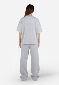 Šedé oversized tričko a odpovídající volné tepláky z měkké látky. Tričko má krátké rukávy a kulatý výstřih, jednobarevné.