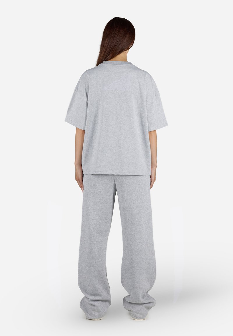 Šedé oversized tričko a odpovídající volné tepláky z měkké látky. Tričko má krátké rukávy a kulatý výstřih, jednobarevné.