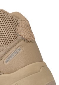 Waterproof beige hiking shoe featuring a textured upper with mesh panels and a smooth rubber sole. Subtle branding on the side.