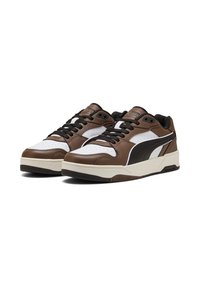 Braune Ledersneaker mit weißen und schwarzen Akzenten, die Perforationen an der Zehenpartie, schwarze Schnürsenkel und eine dicke cremefarbene Sohle aufweisen.